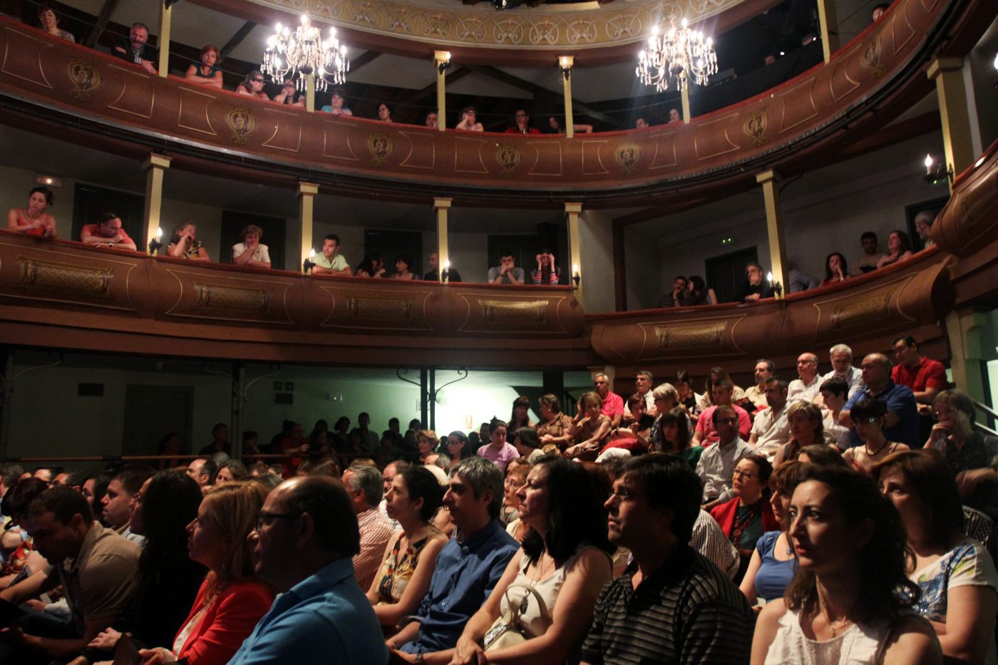 Varias personas disfrutando de una obra teatral en el Corral de Comedias de Alcalá de Henares.