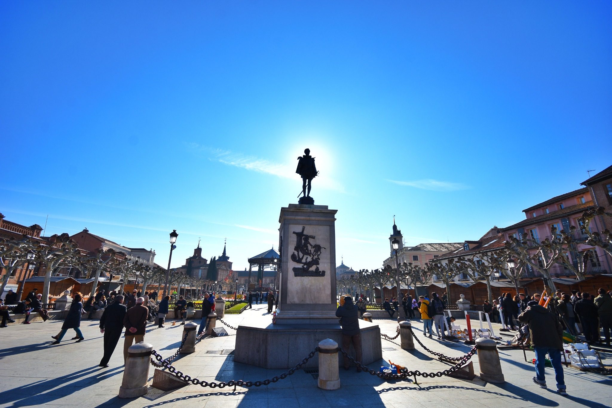 Plano general de la estatua de Cervantes con gente paseando alrededor, en la plaza de cervantes
