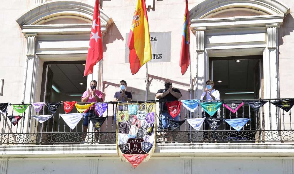 La corporación municipal y las peñas festivas de Alcalá colocan su estandarte en el balcón del Ayuntamiento